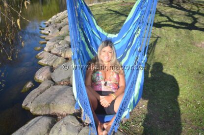 Kvinna njuter i stora drag av att sitta bekvämt och chilla i hängstolen Lagoa medan solen skiner en vacker sommardag.