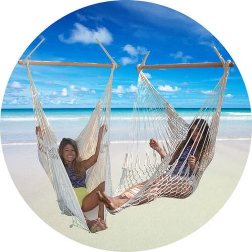 Kategori hängstolar exemplifierad av 2 st handvävda och flätade hänggungor mot blå himmel på en strand med blått hav.